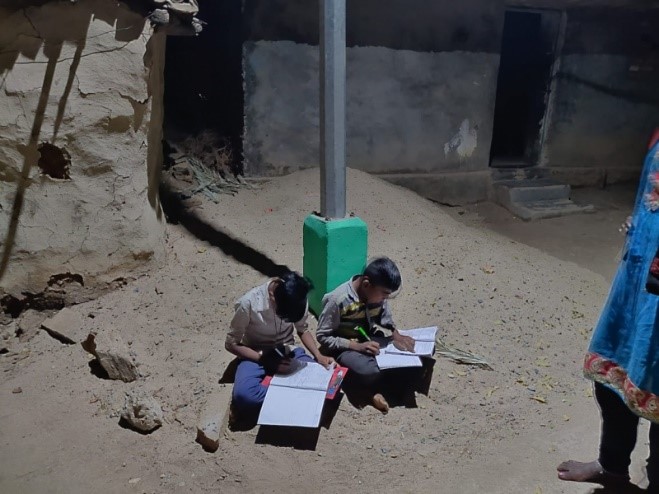 Two children sitting under streetlight doing homework