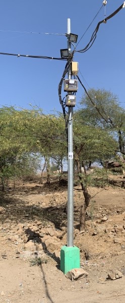 Streetlight installed in ground with green trees in background