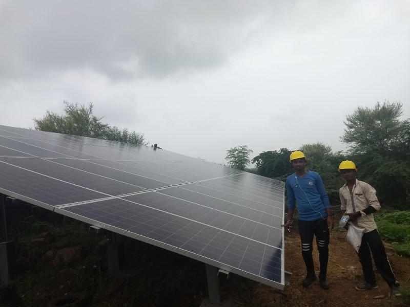 Two workders standing near completed solar panel grid in Tuvar