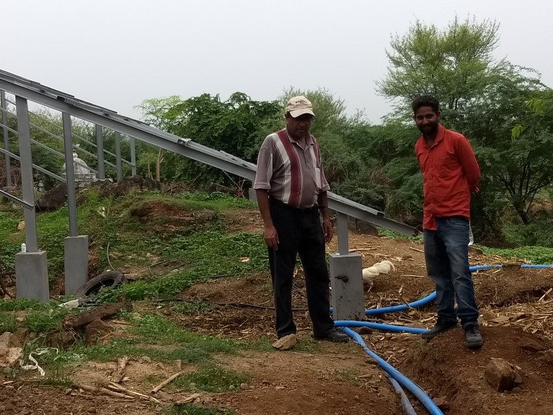 Workers installing power lines in ground near solar panels in Tuvar