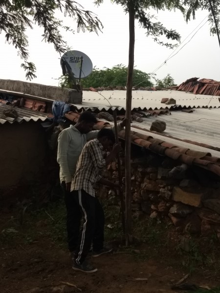 Workers placing wooden pole in ground in Tuvar Village